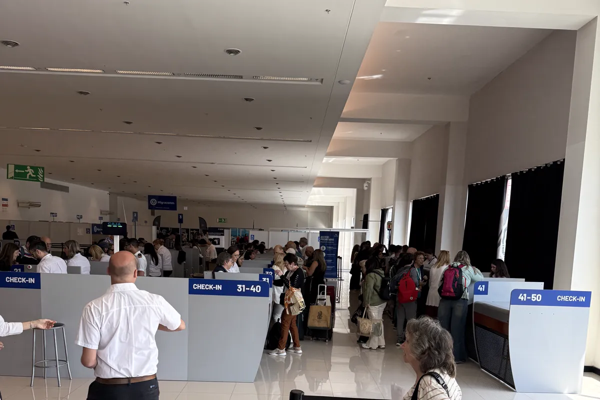 Fila de pasajeros frente a los mostradores de check-in del crucero en la terminal de Buenos Aires el día de embarque