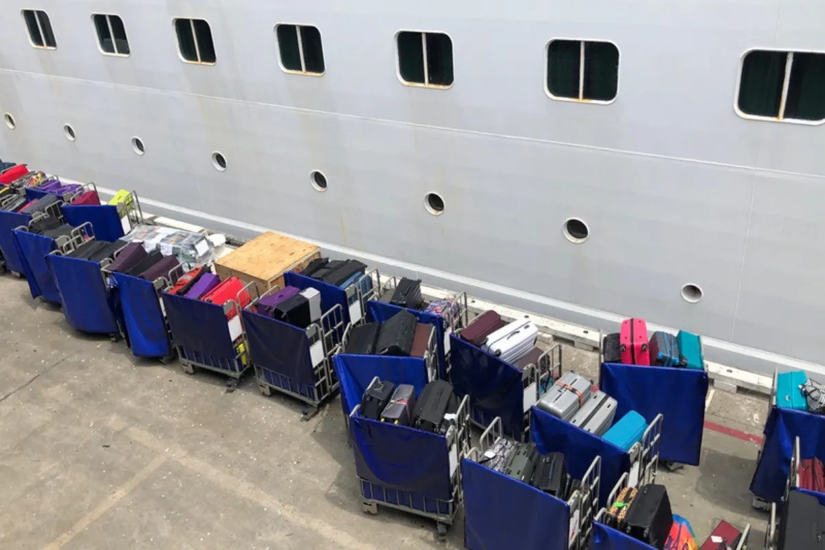 Carros con maletas alineados en el muelle junto al casco del barco, listos para el desembarque