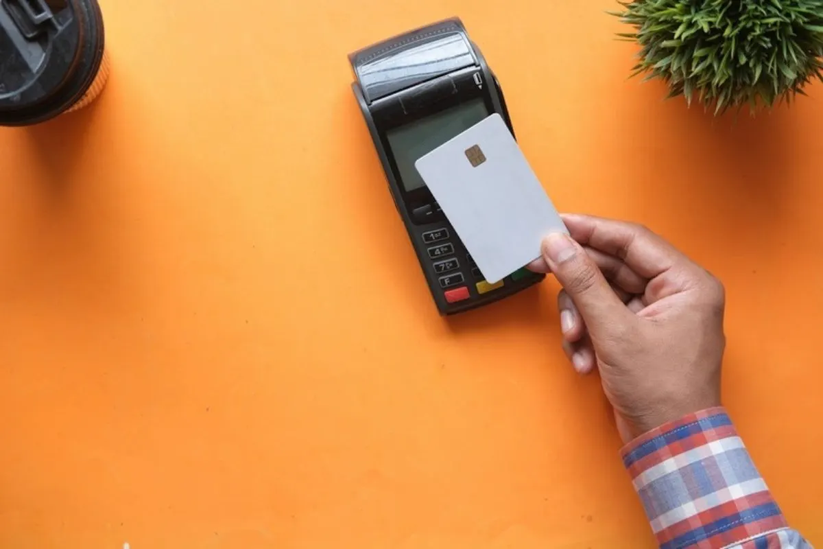 Mano acercando una tarjeta a una terminal de pago