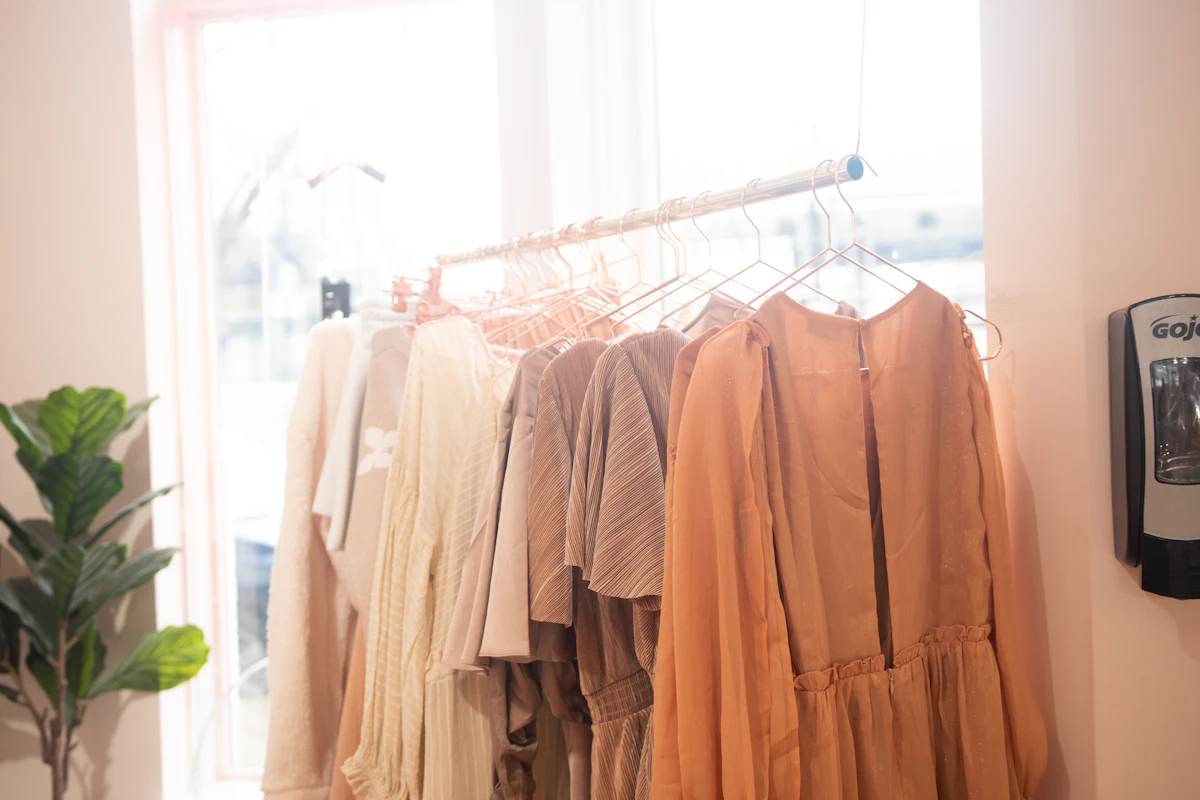 Percha con ropa liviana en tonos claros y rosados colgada junto a una ventana