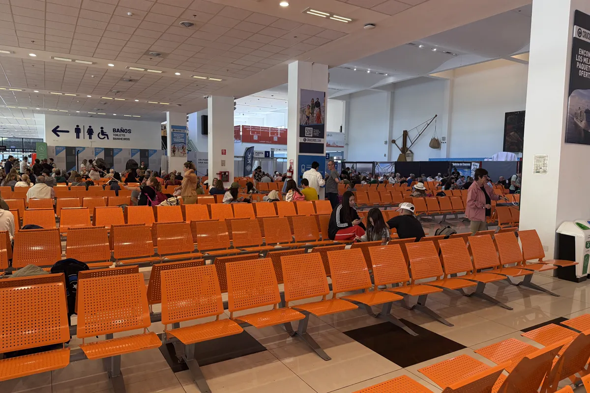 Sala de espera de la terminal de cruceros de Buenos Aires con asientos naranjas y pasajeros esperando su turno de embarque